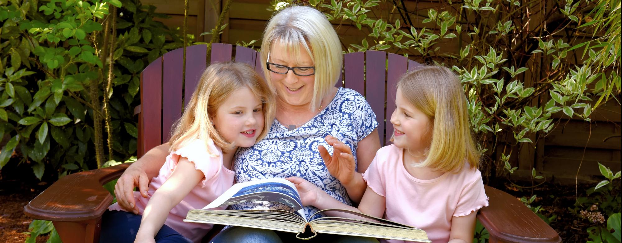 Image of Grandparent with two grandchildren looking at a book
