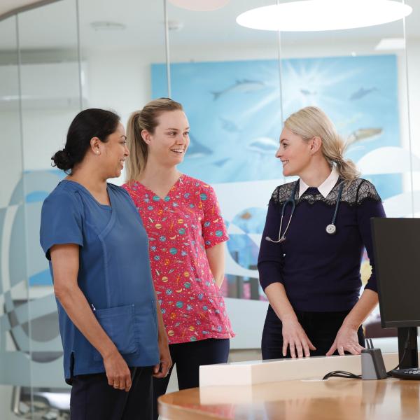 Two nurses and a doctor standing around talking