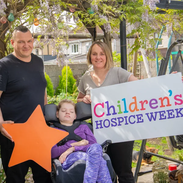 Malgosia's parents standing with Malgosia holdin Children's Hospice Week Branding